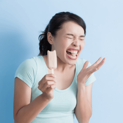 Caring for sensitive teeth 4 Woman cringes after taking a bite of ice cream