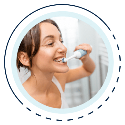 Woman looking in the mirror and brushing her teeth using an electric toothbrush