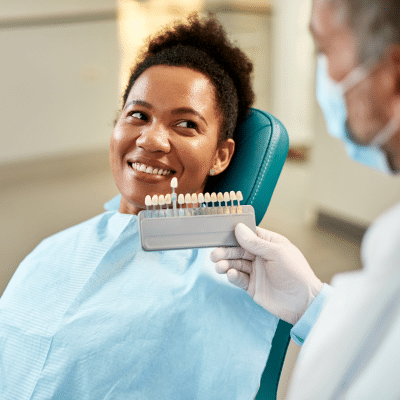 Customizing your dental veneers: shape, size, and color options 7 Woman at dentist choosing color for dental veneers