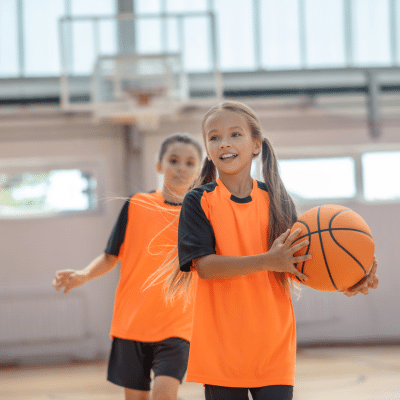 How to prevent sports dental injuries 4 Kids dressed in orange shirts, playing basketball, representing sports dental injuries